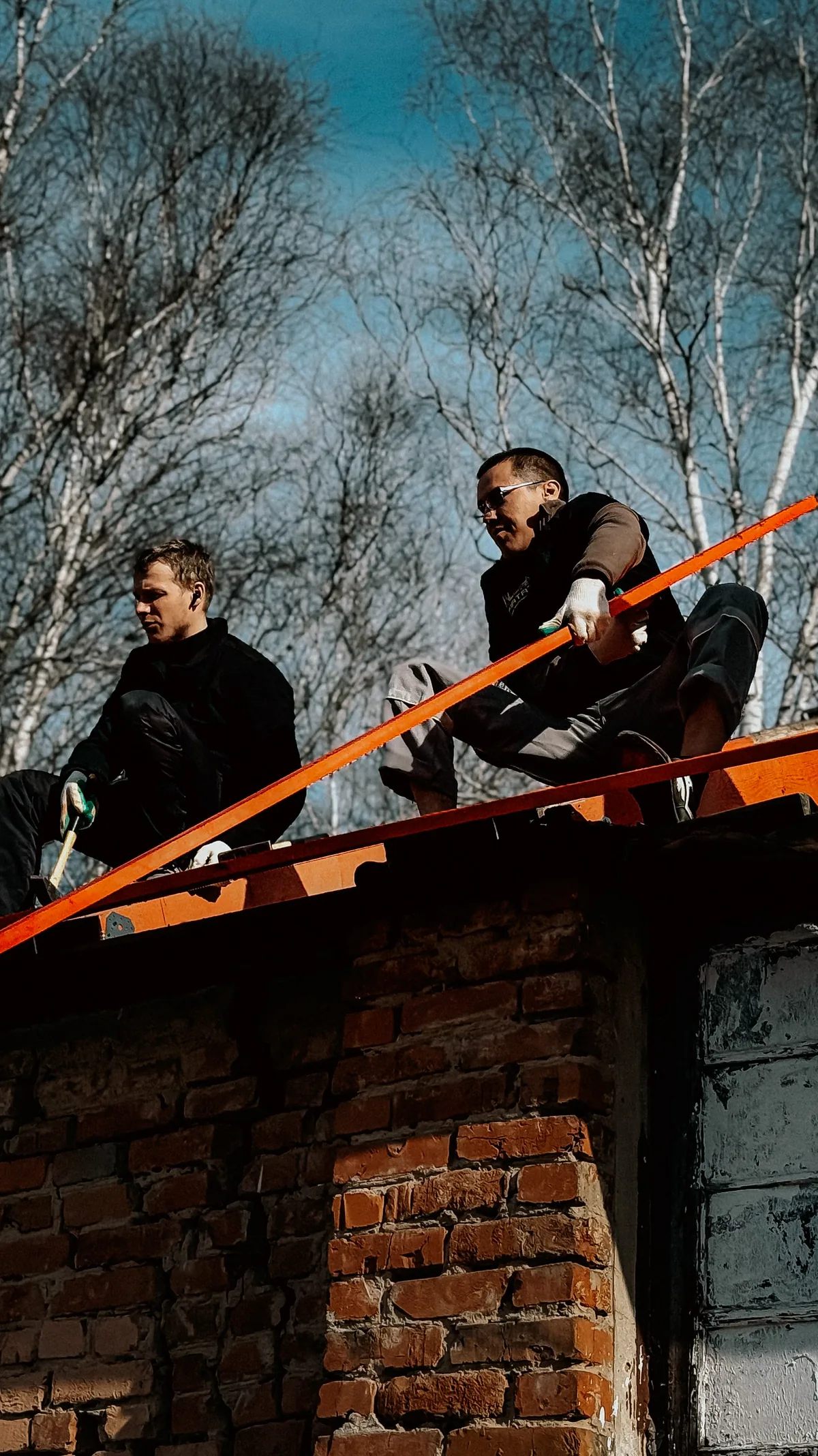 Dos operarios trabajando sobre el faldón de una casa antigua, con el andamio montado en la fachada